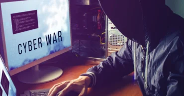 Εικόνα άνδρα με κουκούλα που διαβάζει μια ανακοίνωση για cyber war